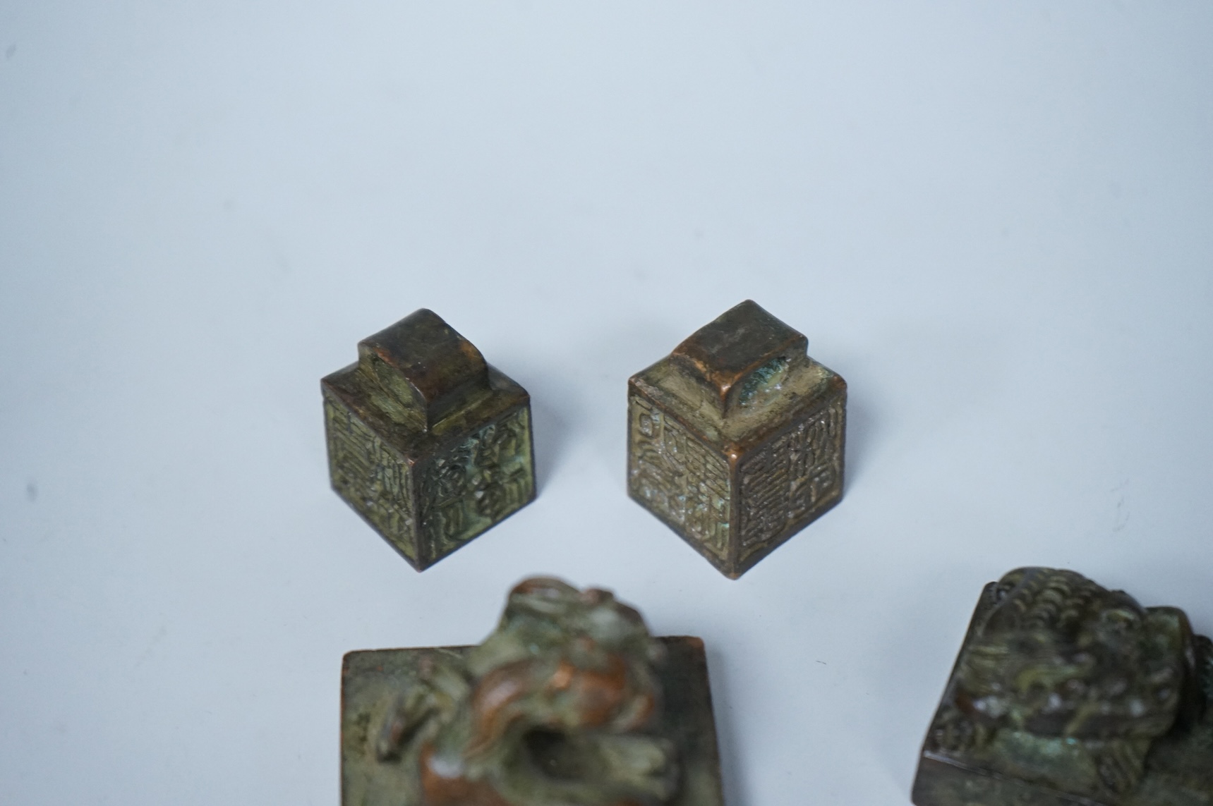 Four Chinese bronze seals, one in the form of two lion dogs, largest 7.5cm wide